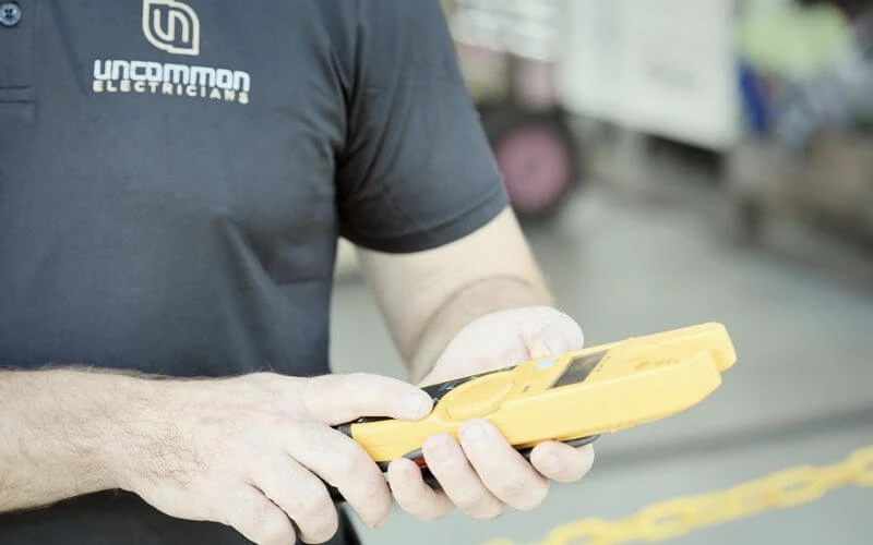 A man using a yellow and black handheld device at home.