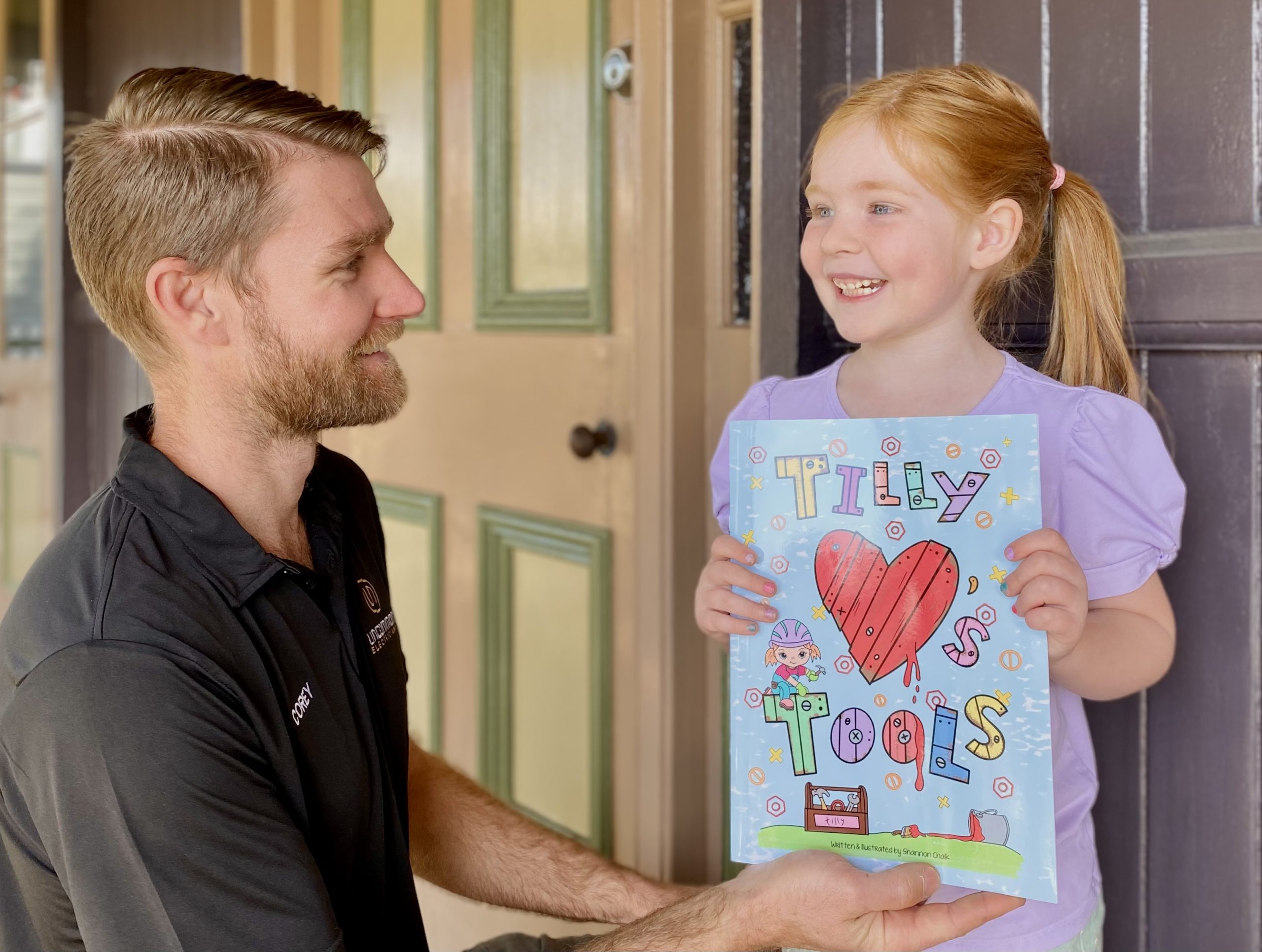 A man holding a sign for a little girl while working as an uncommon electrician.