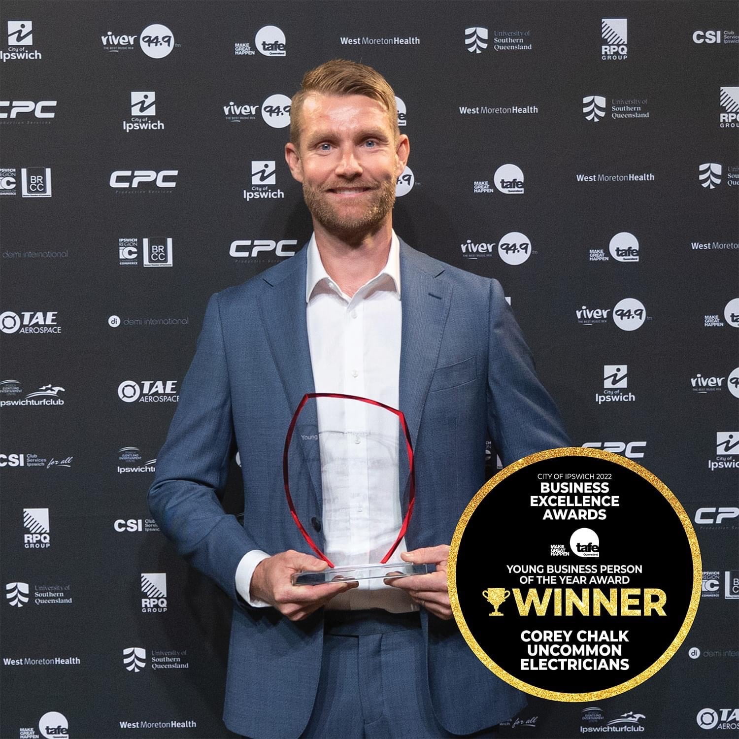 A man holding an award in front of a wall.