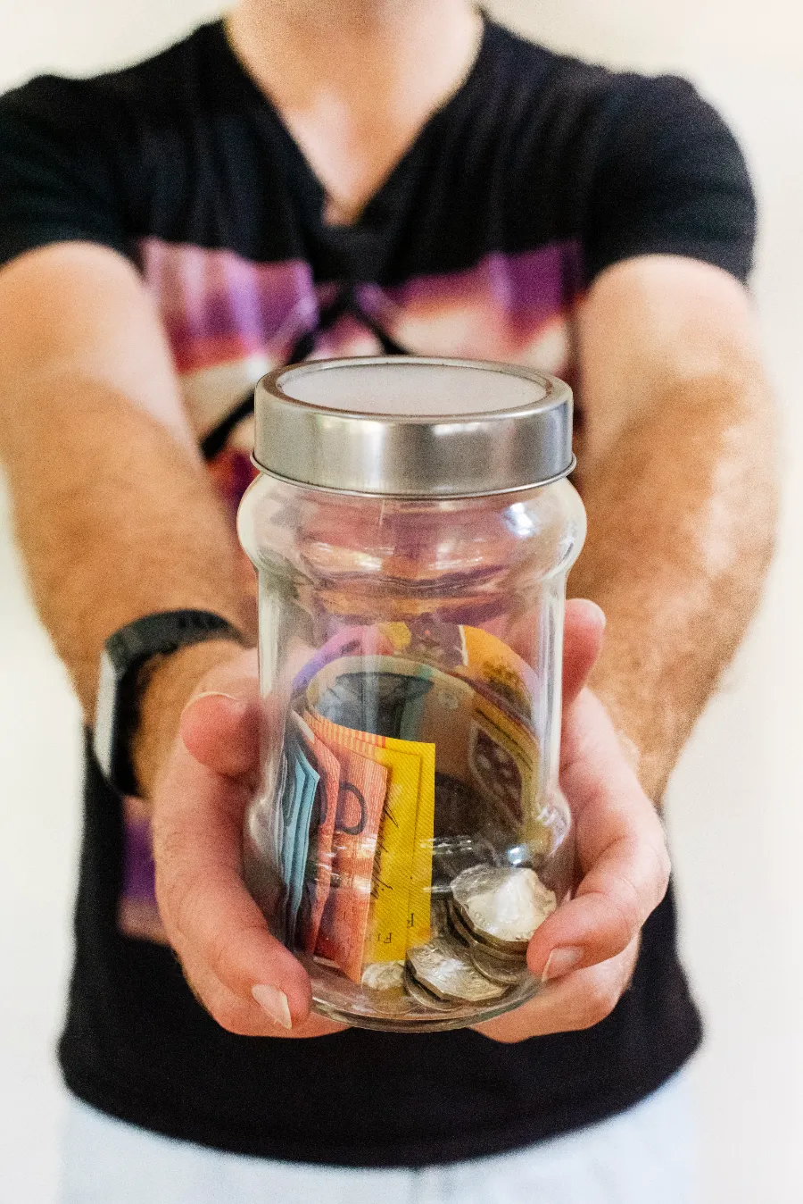 A man holding a jar full of money.