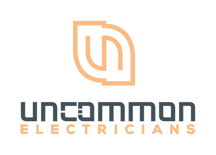 Logo of Uncommon Electricians featuring stylized text in dark grey and light orange, with a design element resembling an abstract leaf or electrical symbol.